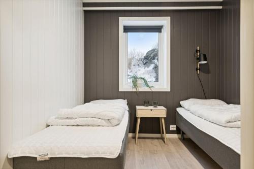 two beds in a room with a window at Stor rorbu med hoy standard in Stamsund