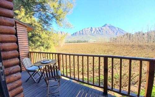 a table and chair on a deck with a view of a mountain at Vindoux Tree House Guest Farm & Spa in Tulbagh