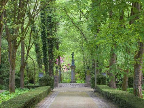a path through a park with a statue in the distance at Fishing Chalet, Opglabbeek in Oudsbergen 
