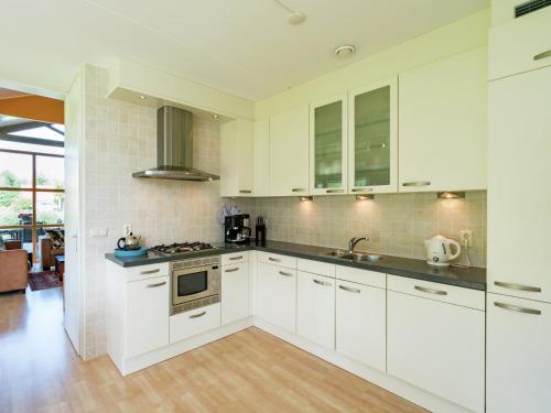 a kitchen with white cabinets and a stove at Villa in Biddinghuizen by Lake Vulwe in Biddinghuizen