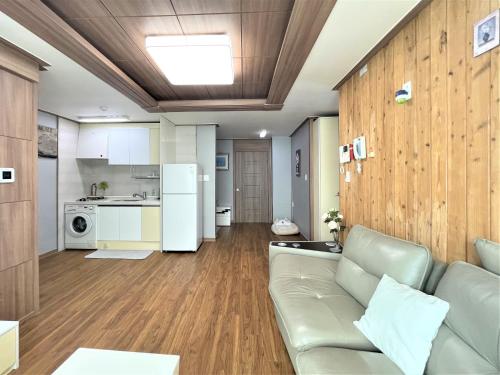 a living room with a couch and a kitchen at HY Choi Hostel in Seogwipo