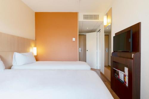a hotel room with two beds and a flat screen tv at ibis Nancy Centre Gare et Congres in Nancy