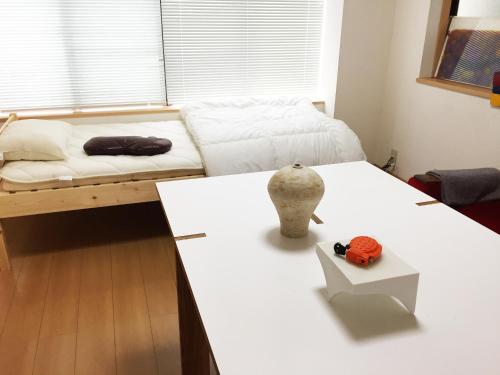 a room with two beds and a white table at Toolate Guesthouse Toyama in Toyama