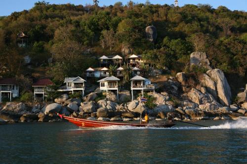 a boat in the water in front of a house at Lighthouse Bungalows in Haad Rin
