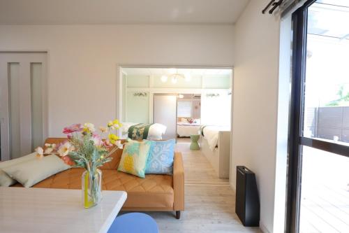 a living room with a couch and a vase of flowers at 戸建て貸切宿 サウナ ジャグジー BBQ 最大8名 駐車場2台 HOTEL DREAM MUSIC Minami-Kujūkuri in Shirako