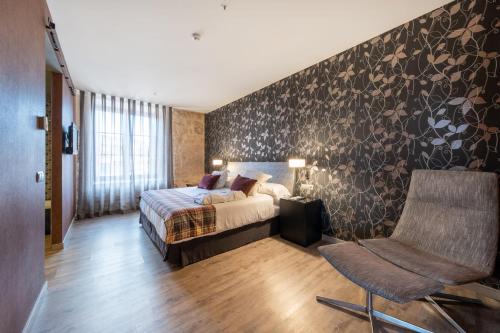 a bedroom with a bed and a chair at Castilla Termal Burgo de Osma in El Burgo de Osma