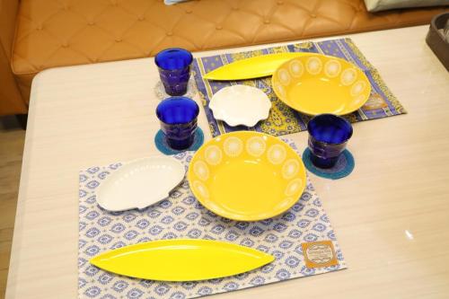 a table with yellow plates and blue glasses on it at 戸建て貸切宿 サウナ ジャグジー BBQ 最大8名 駐車場2台 HOTEL DREAM MUSIC Minami-Kujūkuri in Shirako