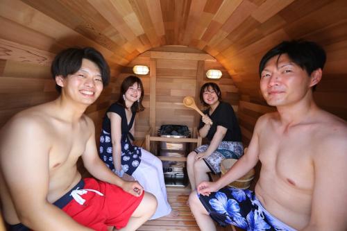 a group of people sitting in a sauna at 戸建て貸切宿 サウナ ジャグジー BBQ 最大8名 駐車場2台 HOTEL DREAM MUSIC Minami-Kujūkuri in Shirako