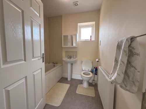 a bathroom with a toilet and a sink and a window at Posh Wetheringsett in Milton Keynes in Milton Keynes