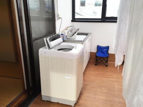 a white washing machine in a bathroom with a window at Toolate Guesthouse Toyama in Toyama