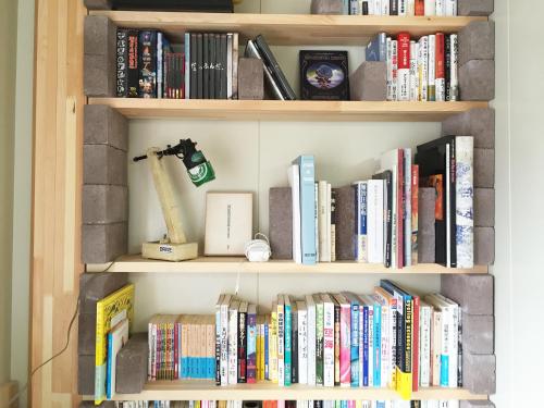 a book shelf filled with lots of books at Toolate Guesthouse Toyama in Toyama