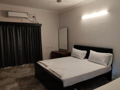 a bedroom with a bed with white sheets and a window at Umino Beach House in Covelong