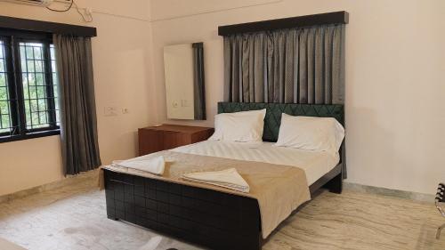 a bedroom with a large bed with a black headboard at Umino Beach House in Covelong