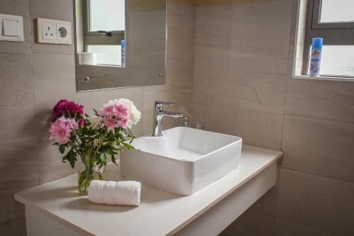 a bathroom with a sink and flowers on a counter at Bois Mapou Self Catering Apartments Unit 203 in Rivière Noire
