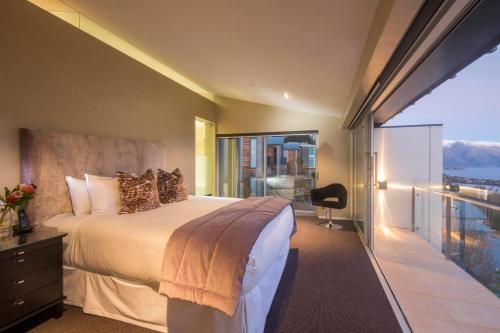 a bedroom with a large bed and a balcony at Villa De Luxe, a Relax it's Done luxury holiday home in Queenstown