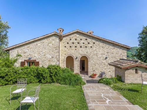 a stone building with chairs in front of it at Beautiful Villa in Belforte all'Isauro with Swimming Pool in Belforte allʼIsauro