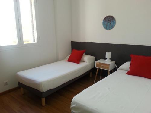 two beds in a room with two red pillows at Malhara in Seville