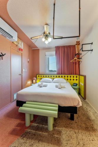 a bedroom with a large bed with a yellow headboard at greet hôtel Pont du Gard - Route d'Avignon in Estézargues