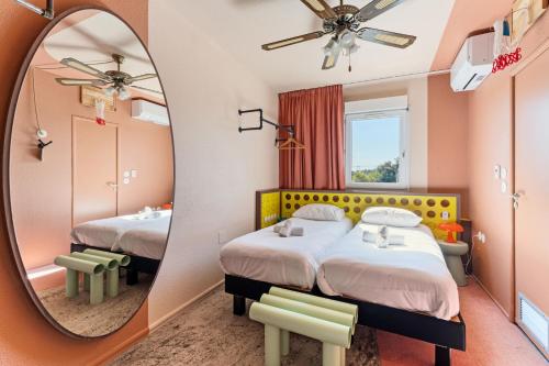 a room with two beds and a mirror at greet hôtel Pont du Gard - Route d'Avignon in Estézargues