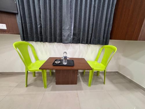 two green chairs and a table and a table and chairs at Dwarka Lodging in Pune
