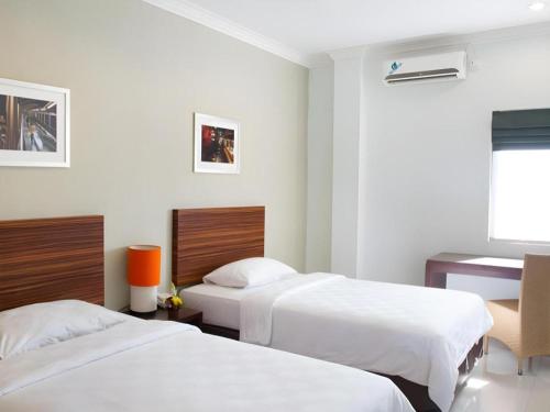 a hotel room with two beds and a desk at The Studio Inn Nusa Dua in Ubud