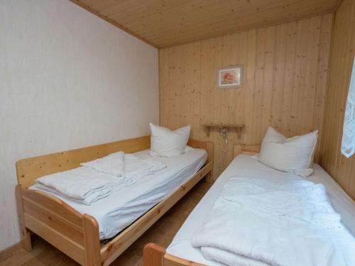 two twin beds in a room with wooden walls at Welcoming bungalows in Neustadt in Neustadt/Harz