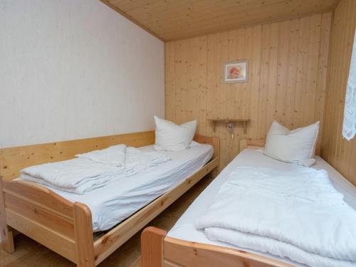 two beds in a room with wooden walls at Welcoming bungalows in Neustadt in Neustadt/Harz