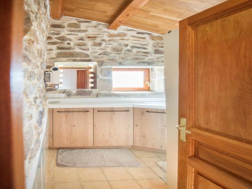 a kitchen with wooden cabinets and a stone wall at Detached holiday home in Chassiers with pool in Chassiers