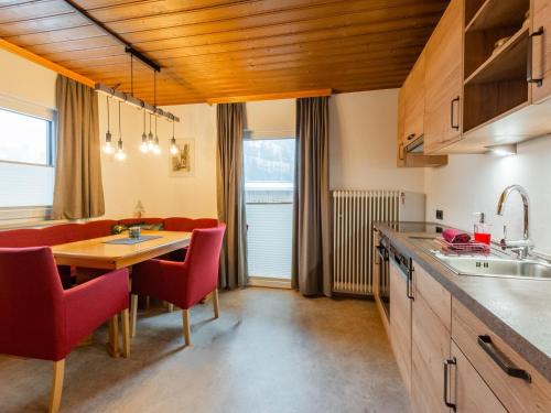 a kitchen and dining room with a table and red chairs at Modern Apartment in Kitzbuhel near Ski Area in Kitzbühel