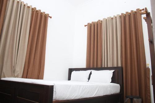 a bed with brown curtains and a bed with white pillows at Meera Bayside Villas in Oddaimavadi