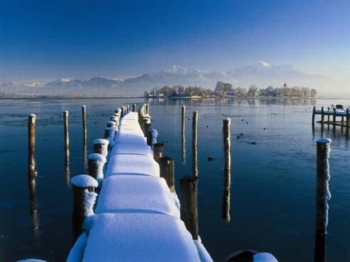 a dock covered in snow on a body of water at Eco-friendly chalet near the lake in Asten in Tittmoning