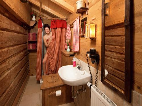 a woman is standing in the shower in a wooden bathroom at Eco-friendly chalet near the lake in Asten in Tittmoning