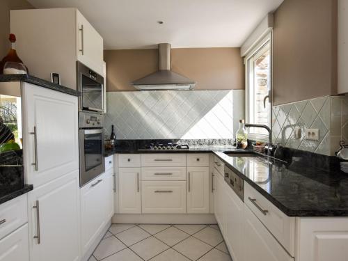 エピニアックにあるPeaceful Garden Retreat, Epiniacの白いキャビネットと黒いカウンタートップを備えたキッチン