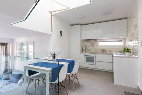 a kitchen with white cabinets and a blue table and chairs at Apartment Art in Krk