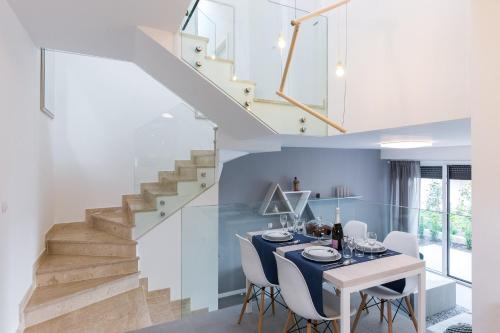 un comedor con mesa y sillas y una escalera en Apartment Art, en Krk