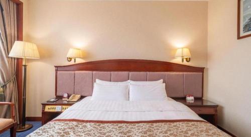 a hotel room with a bed with two lamps and a telephone at Quanzhou Hotel in Quanzhou