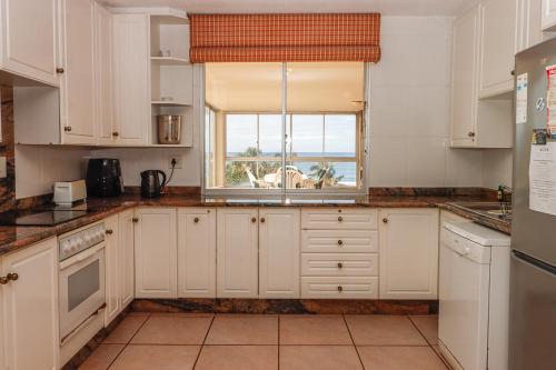 Una cocina con gabinetes blancos y una ventana. en Rondevoux 16, en Margate