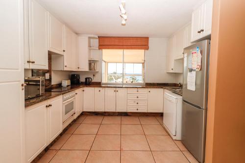 Una cocina con gabinetes blancos y un refrigerador de acero inoxidable. en Rondevoux 16, en Margate