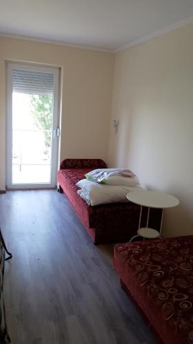 a room with two beds and a table and a window at Vízparti apartmanok in Szántód