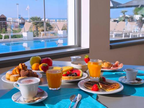 a table topped with plates of breakfast foods and drinks at Hotel Delle Nazioni - Adults Only in Caorle