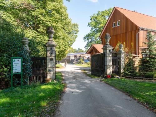 a gate to a driveway with a house and a barn at Blockhäuser auf Reiterhof in Eschede in Eschede