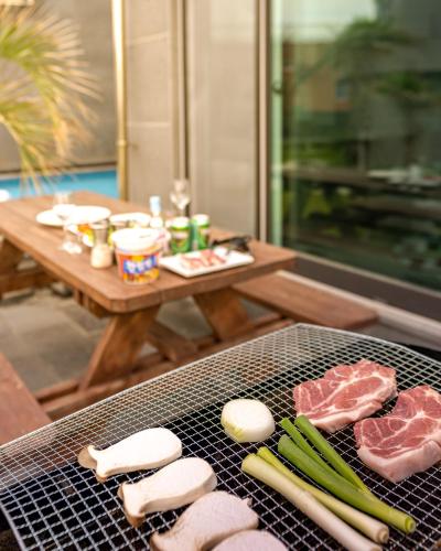 a grill with meat and vegetables on a table at Pool Story 6 in Jeju