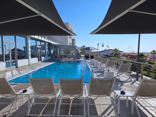 a row of chairs and a swimming pool at Hotel Delle Nazioni - Adults Only in Caorle