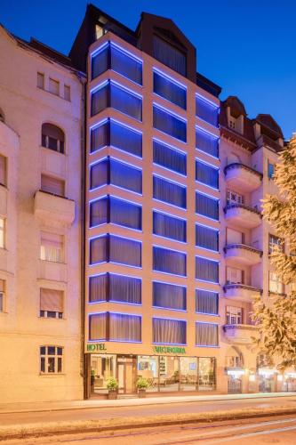a tall building with blue windows on a street at Boutique Hotel Victoria Budapest in Budapest