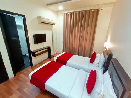 a bedroom with two beds with red pillows at Hotel Sun Grand in Agra