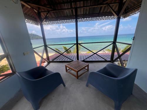 a room with chairs and a table and the ocean at 1511 Coconut Grove in Tioman Island