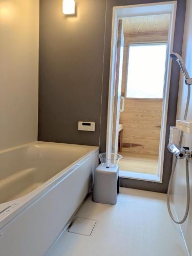a bathroom with a bath tub and a window at 南阿蘇サウナ5gaku G5 in Minami Aso