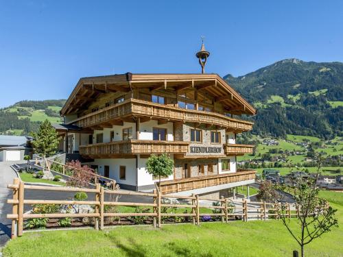 a large wooden building with a fence and mountains at Farmhouse in Schwendau with Ski Storage in Hippach