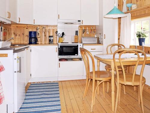 a kitchen with white cabinets and a table and chairs at 4 person holiday home in Vetlanda in Lillarp