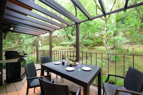 eine Terrasse mit einem Tisch, Stühlen und einem Grill in der Unterkunft Serenity Springs Villa Morita in Hakone
